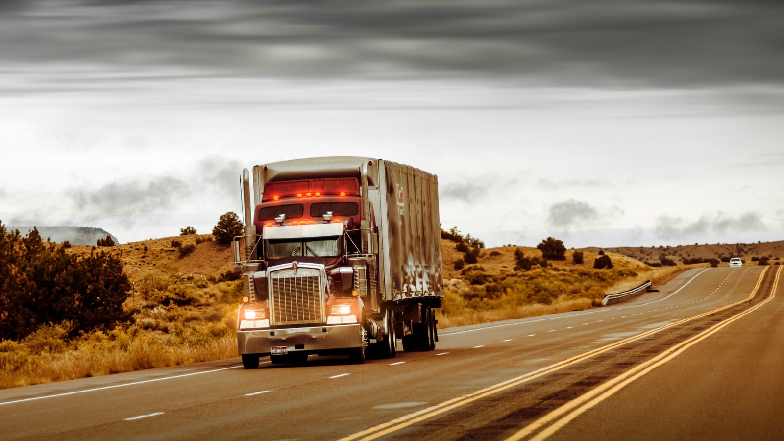 Semi truck hauling a trailer down an open desert highway